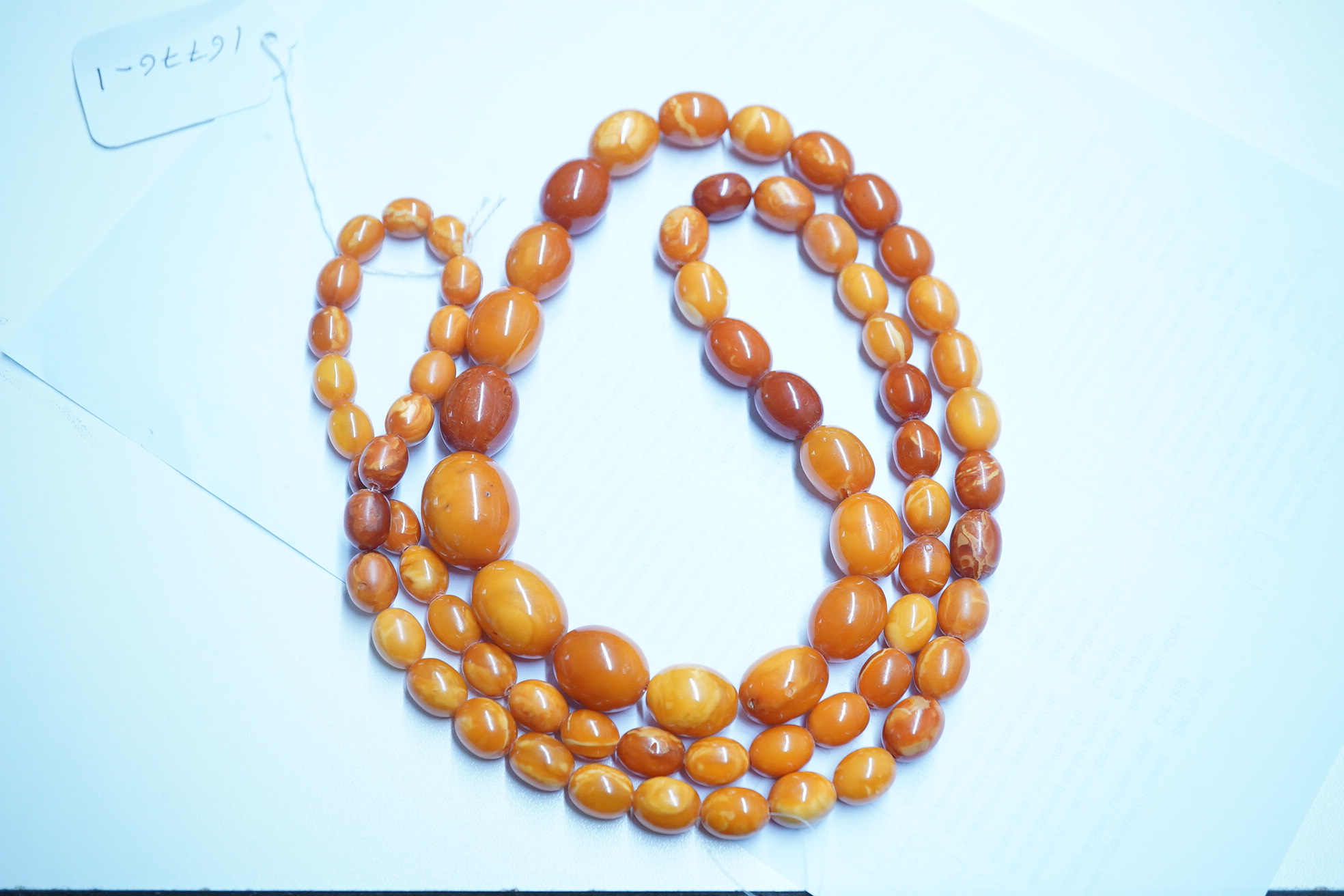 A single strand graduated oval amber bead necklace, 110cm, gross weight 103 grams. Condition - poor to fair